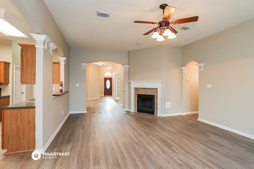 an empty living room with a ceiling fan and a fireplace