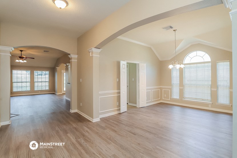 an empty living room with a large window and wood flooring