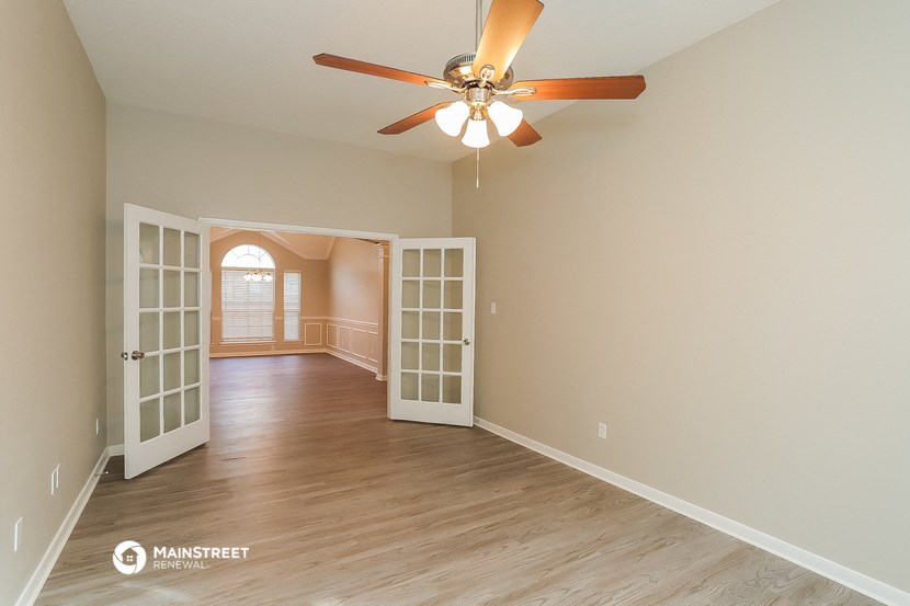 an empty living room with a ceiling fan