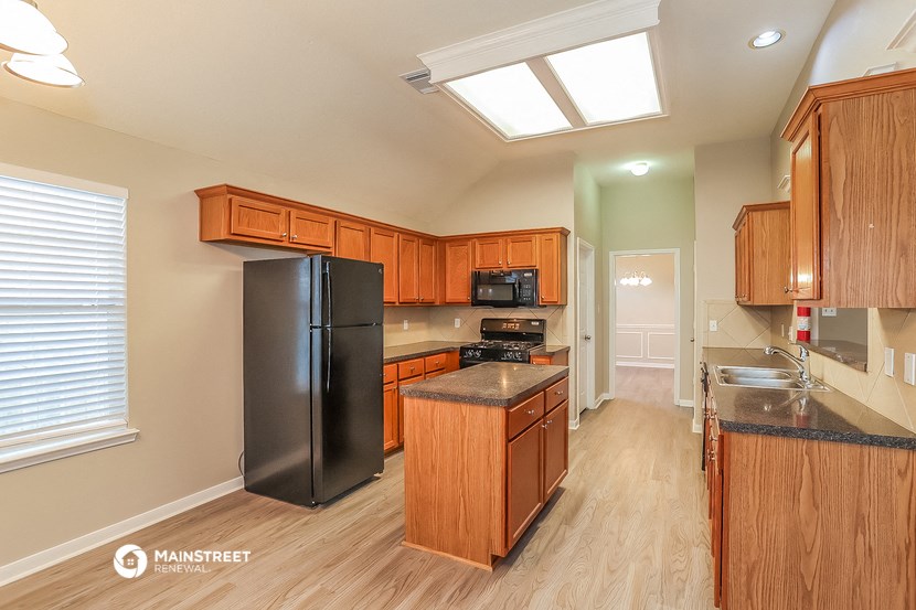 a kitchen with wooden cabinets and a black refrigerator
