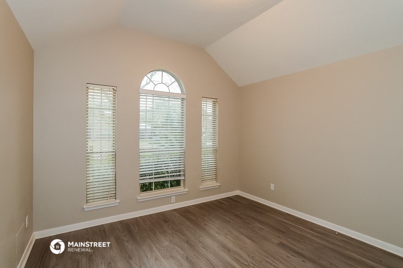an empty living room with wood floors and a large window