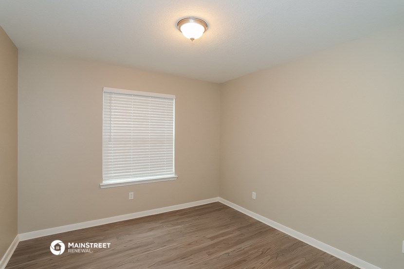 the spacious living room with hardwood flooring and a window