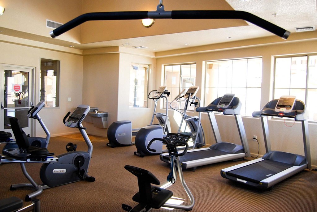 a gym with various exercise machines and windows