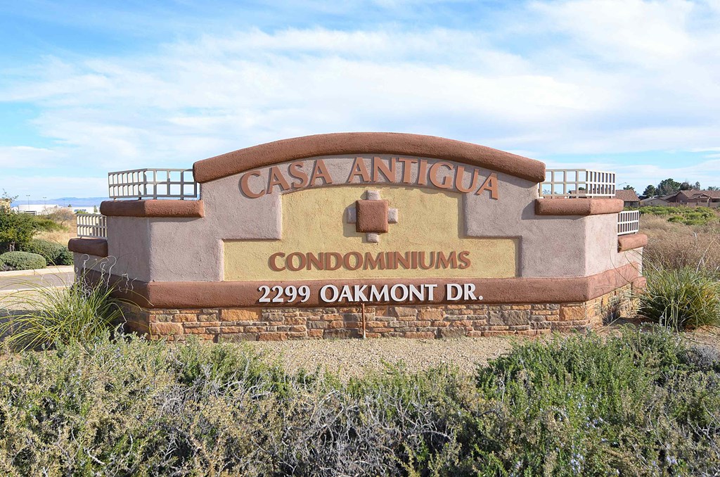 a sign for the antigua condominiums in front of grass
