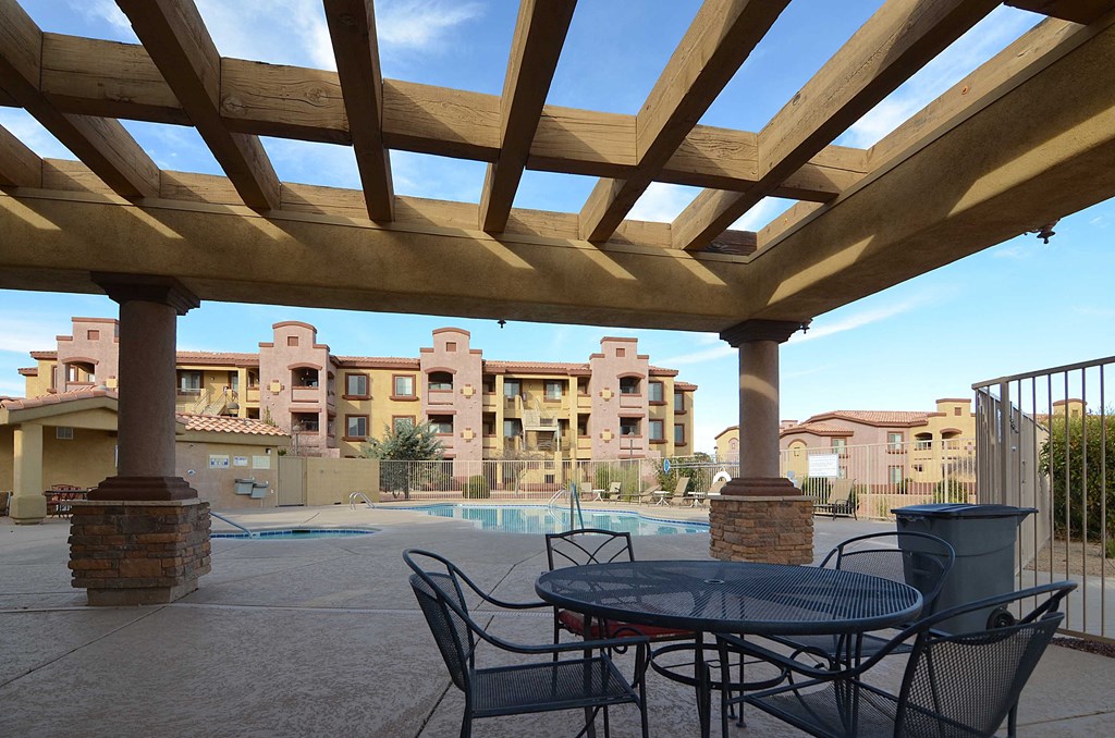 a patio with a table and chairs in front of a swimming pool