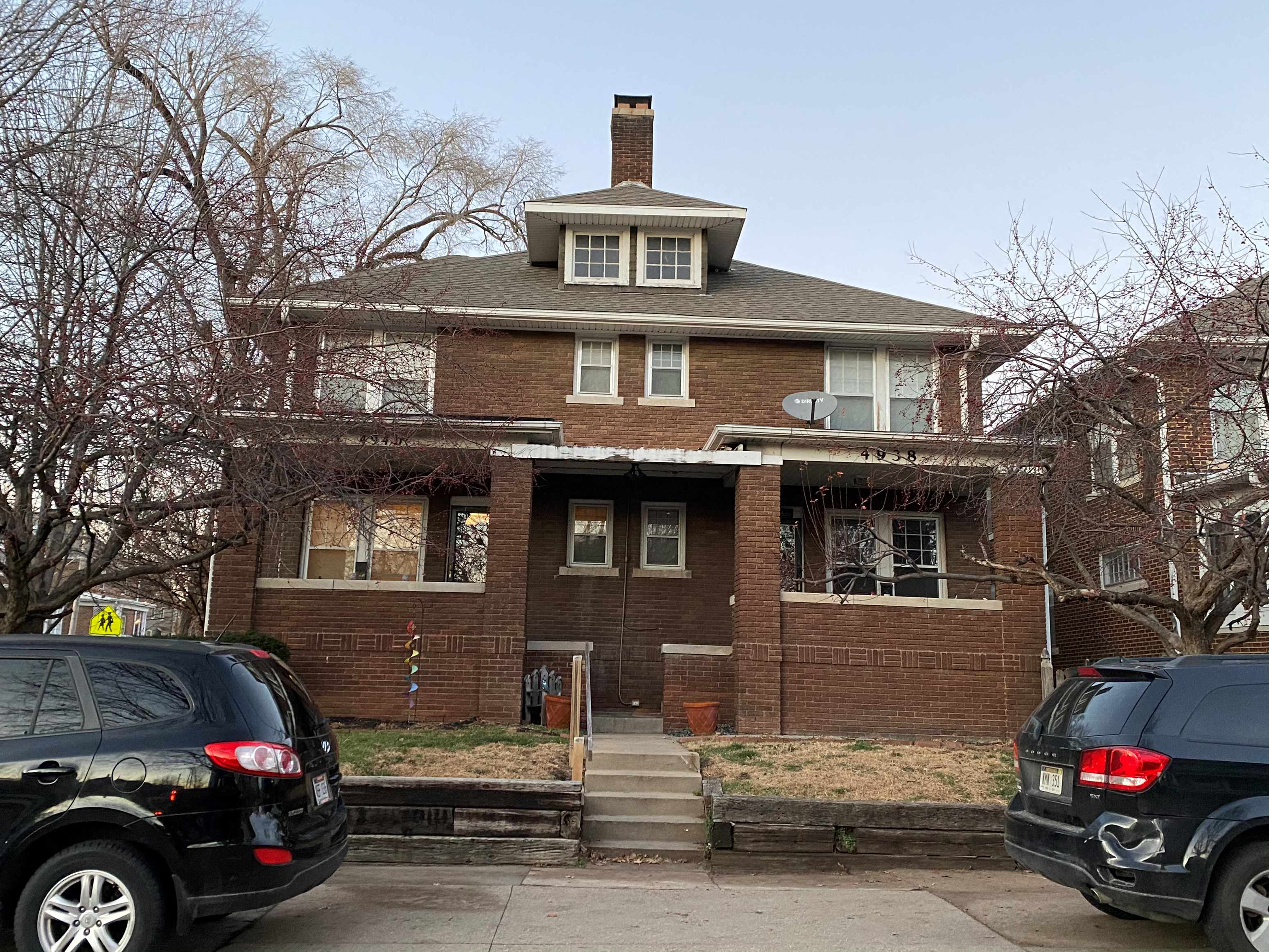 a brick house with cars parked in front of it
