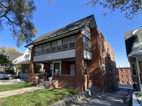 a red brick house with a black roof and a sidewalk