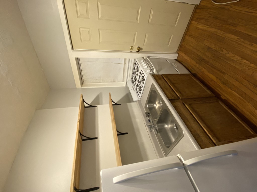 a small kitchen with white cabinets and a refrigerator and a dishwasher
