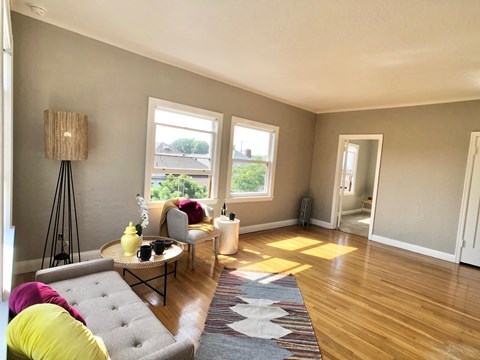 A living room with a grey couch and a yellow pillow.