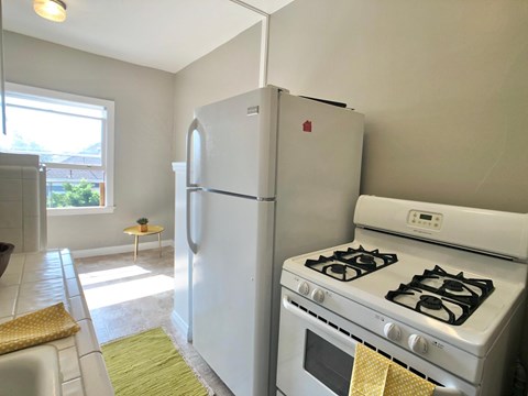 A white refrigerator and stove in a kitchen with a yellow towel hanging on the stove.