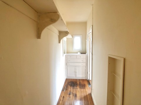 A long hallway with a wooden floor and white walls.