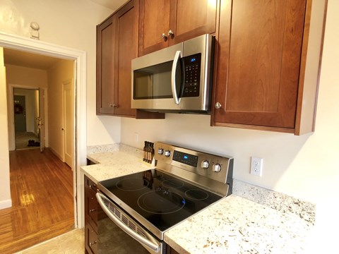 A kitchen with a stove and microwave above it.