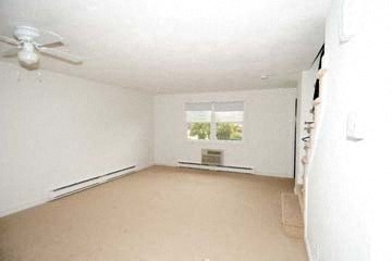 an empty living room with a ceiling fan and a window