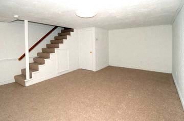 an empty living room with a staircase and a white wall