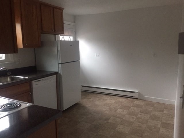 an empty kitchen with a refrigerator and a sink