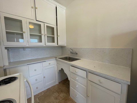 A kitchen with white cabinets and a marble countertop.