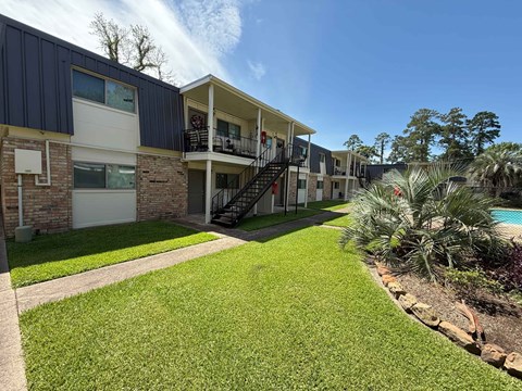 A sunny day at a residential complex with a well-kept lawn and a pool.
