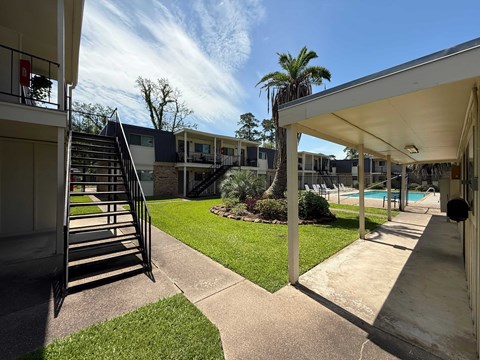 A sunny day at a residential complex with a pool and palm trees.