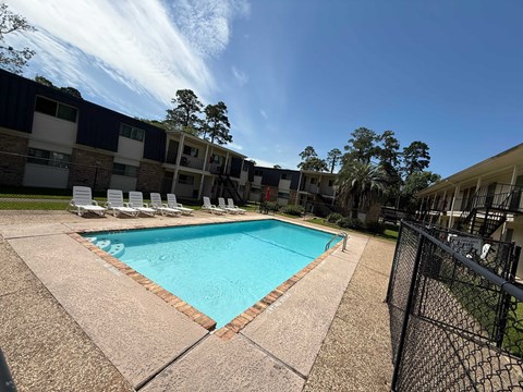 A swimming pool surrounded by a black fence and chairs.
