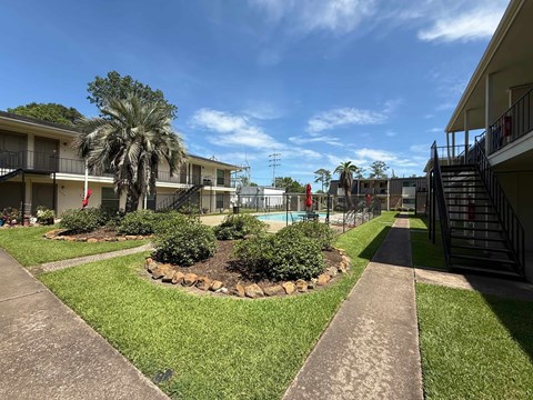 A sunny day at a residential complex with a pool and palm trees.
