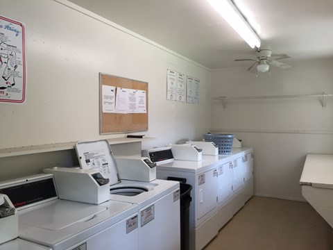 A laundromat with washers and dryers and a fan.