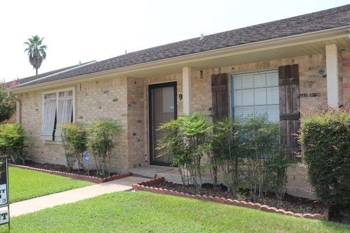 a brick house with a front porch and a lawn
