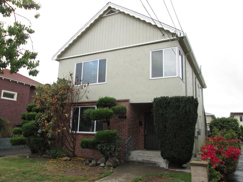 A house with a grey roof and a red brick wall.