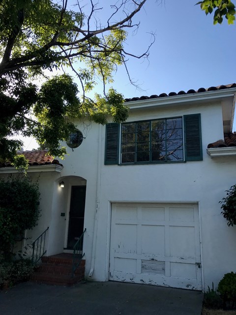A white house with a black door and a white garage door.
