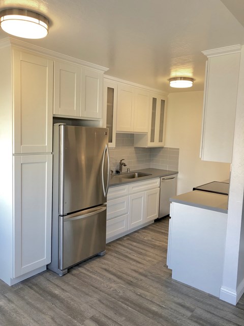 A kitchen with a stainless steel refrigerator and white cabinets.