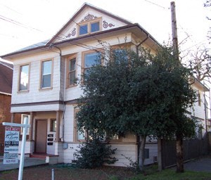 A two-story house with a tree in front.