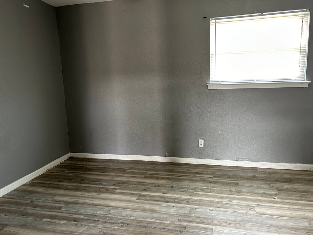 a room with grey walls and a window and wooden floors