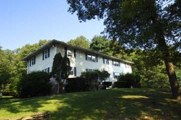a white house on a hill with trees