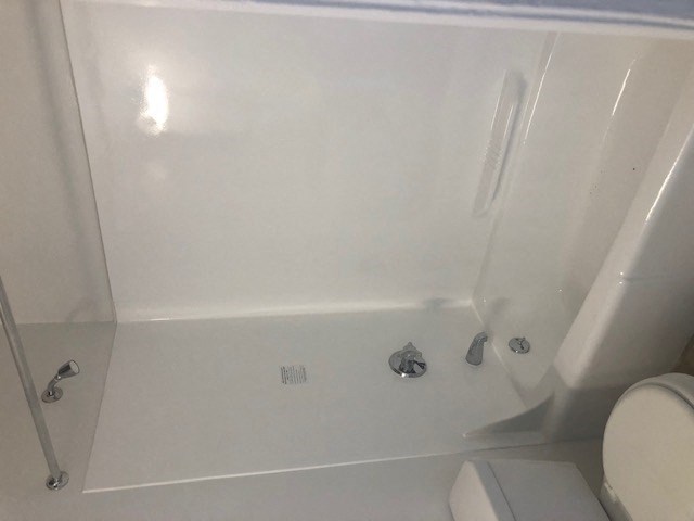 a white bathroom with a toilet and a bath tub