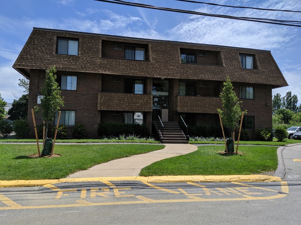 a brick apartment building with a sidewalk in front of it