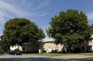 a house with a car parked in front of some trees