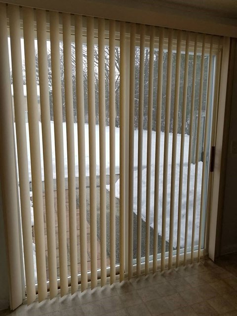 a room with a sliding glass door and blinds
