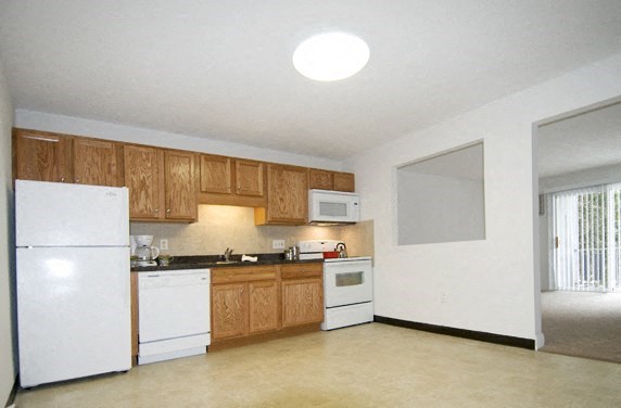 a large kitchen with white appliances and wooden cabinets