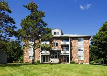 a large brick house with a green lawn and trees