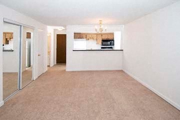 a empty living room with a kitchen and a mirror