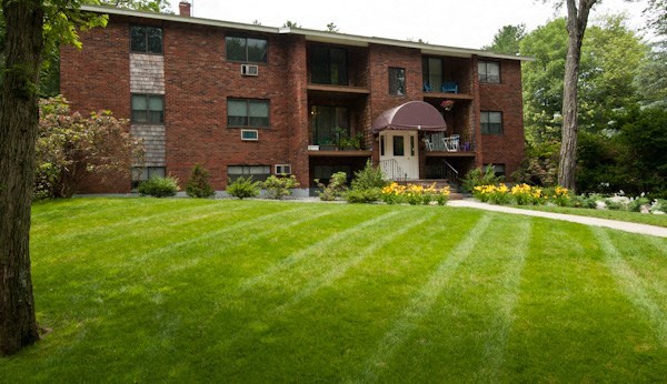 a red brick apartment building with a green lawn