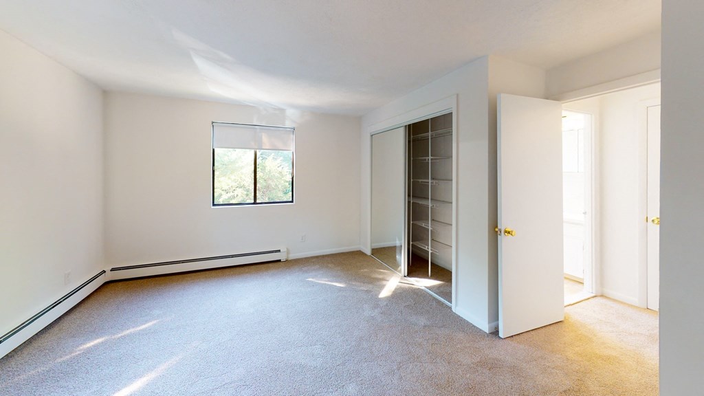 an empty living room with white walls and a door to a closet