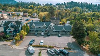 an aerial view of a large green house with cars in a parking lot