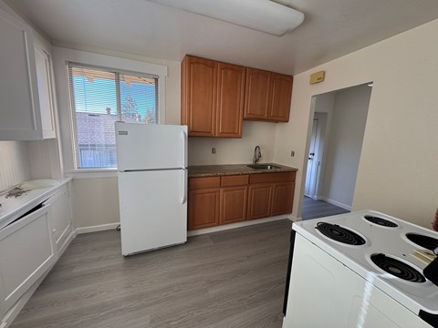 A kitchen with white appliances and wooden cabinets.