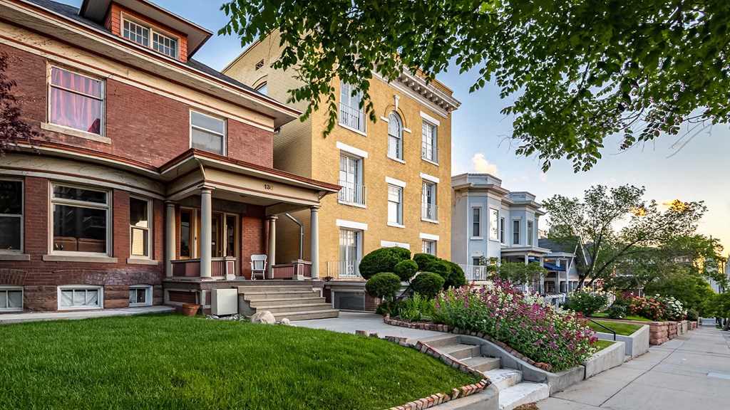 Front exterior of red brick home next to a yellow home for First Avenue Homes