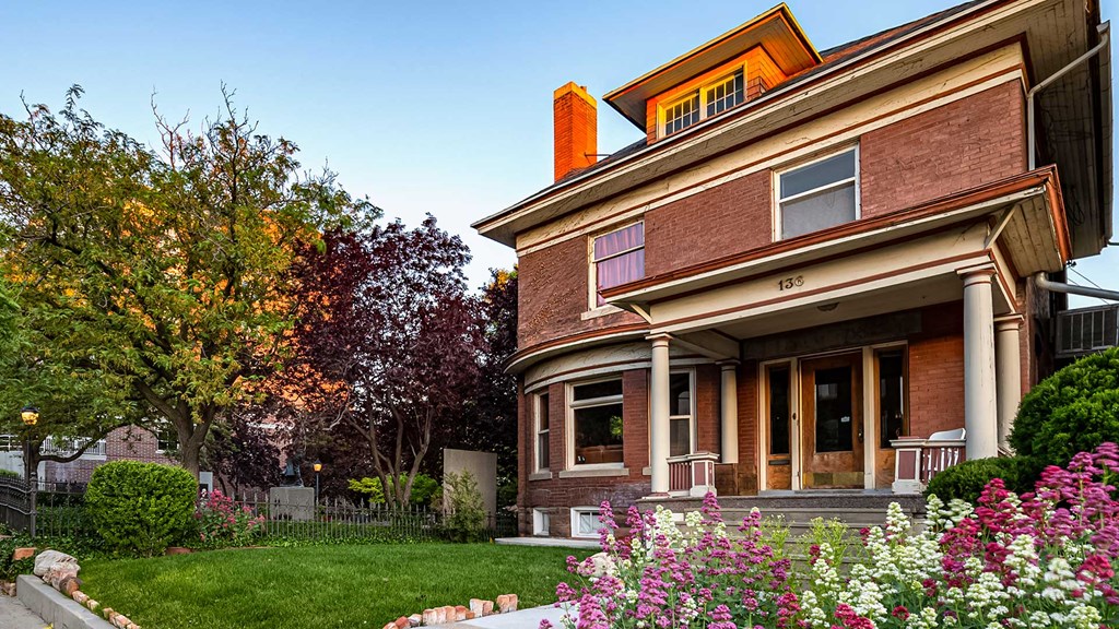 Side exterior view of red brick First Avenue Home with flowers in front of it