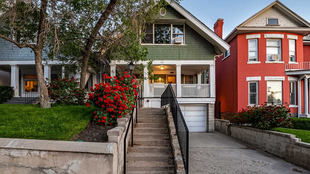 Front exterior view of green First Avenue home with a rose bush