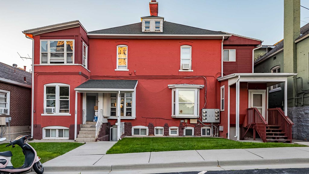 Front exterior of red First Avenue Homes with a view of the front yard