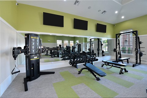 A gym with a variety of equipment including a weight machine, bench, and dumbbells.