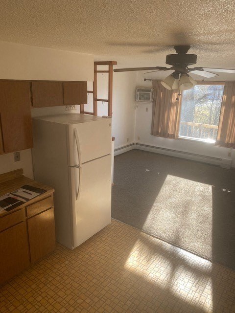 an empty kitchen with a refrigerator and a ceiling fan