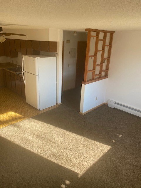 an empty kitchen with a refrigerator and a window